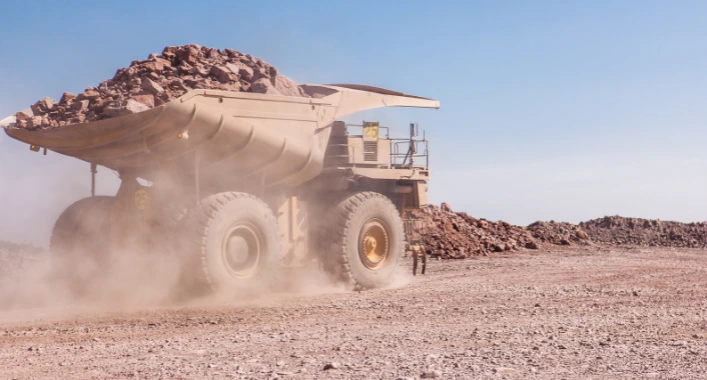 Dust clouds rising from a dry haul road, spreading into the air with reduced visibility